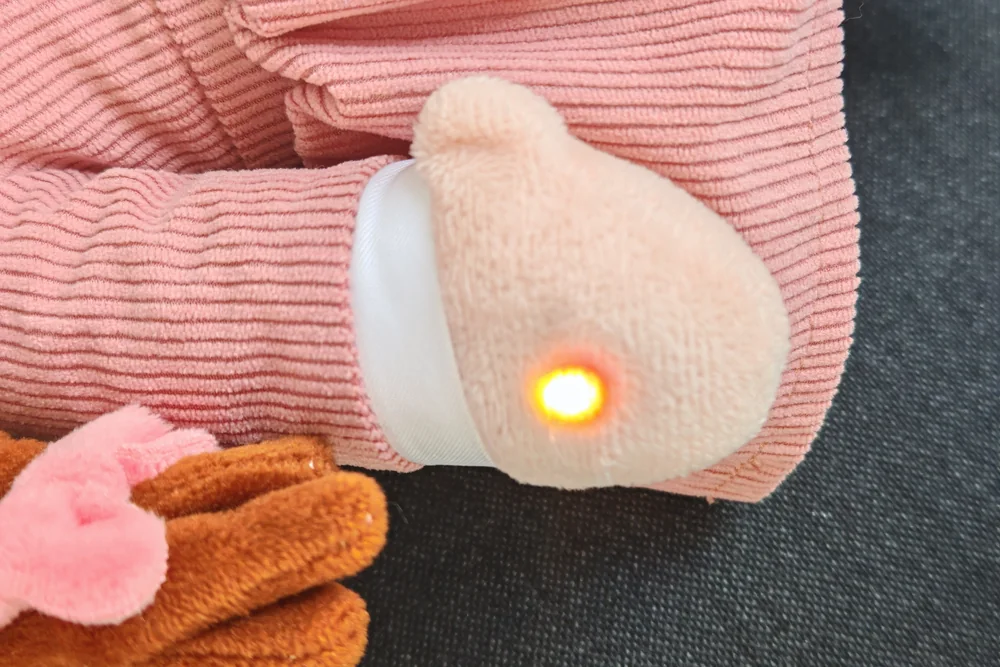 The same hand with the status light glowing yellow while the toy answers
