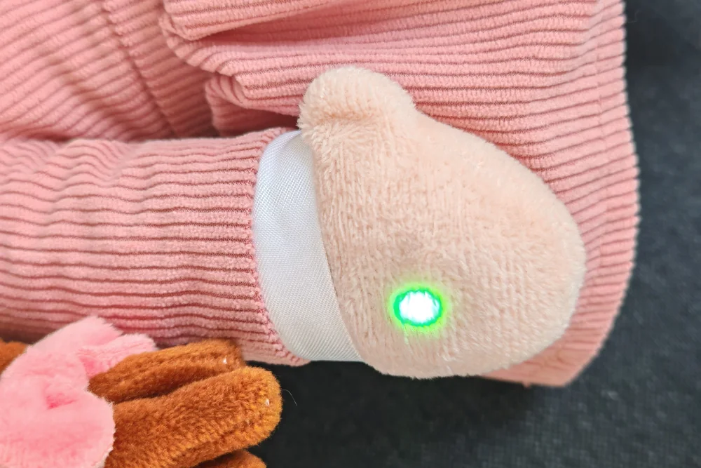 The Playnitive plush toy's hand with the status light glowing green