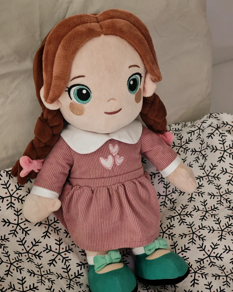 Playnitive Lotti, a plush doll with plaited ginger hair, a dusty pink corduroy dress and teal shoes.